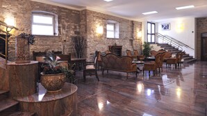 Un vestíbulo amplio con paredes de piedra, suelo de madera pulida y una escalera que conduce a un nivel superior.