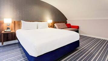 Una habitación de hotel moderna con una cama grande, un techo curvo y una alfombra a rayas.