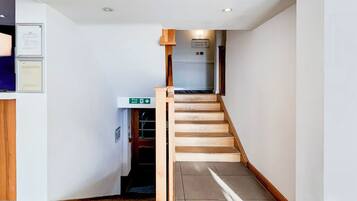 A staircase with a wooden handrail and a fire exit sign.
