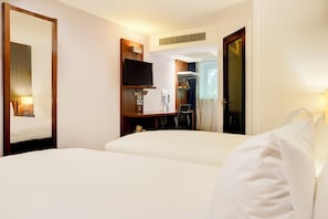Ein Hotelzimmer mit Bett, Fernseher, Schreibtisch und Kleiderschrank.
