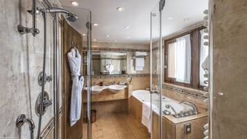Une salle de bain luxueuse dotée d’une douche à parois de verre, de deux vasques, d’une baignoire et d’un grand miroir.