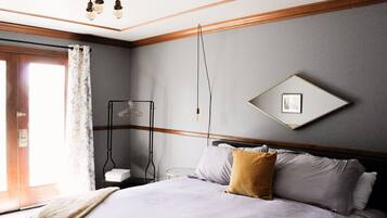 A neatly arranged hotel room with a bed, a bedside table, a hanging light fixture, and a framed picture on the wall.