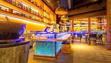 Een bargedeelte met flessen op planken, een bar en zitplaatsen.
