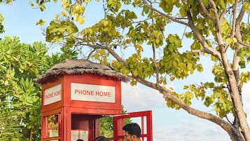 Eine rote Telefonzelle mit der Aufschrift „PHONE HOME“, vor der eine Familie steht.