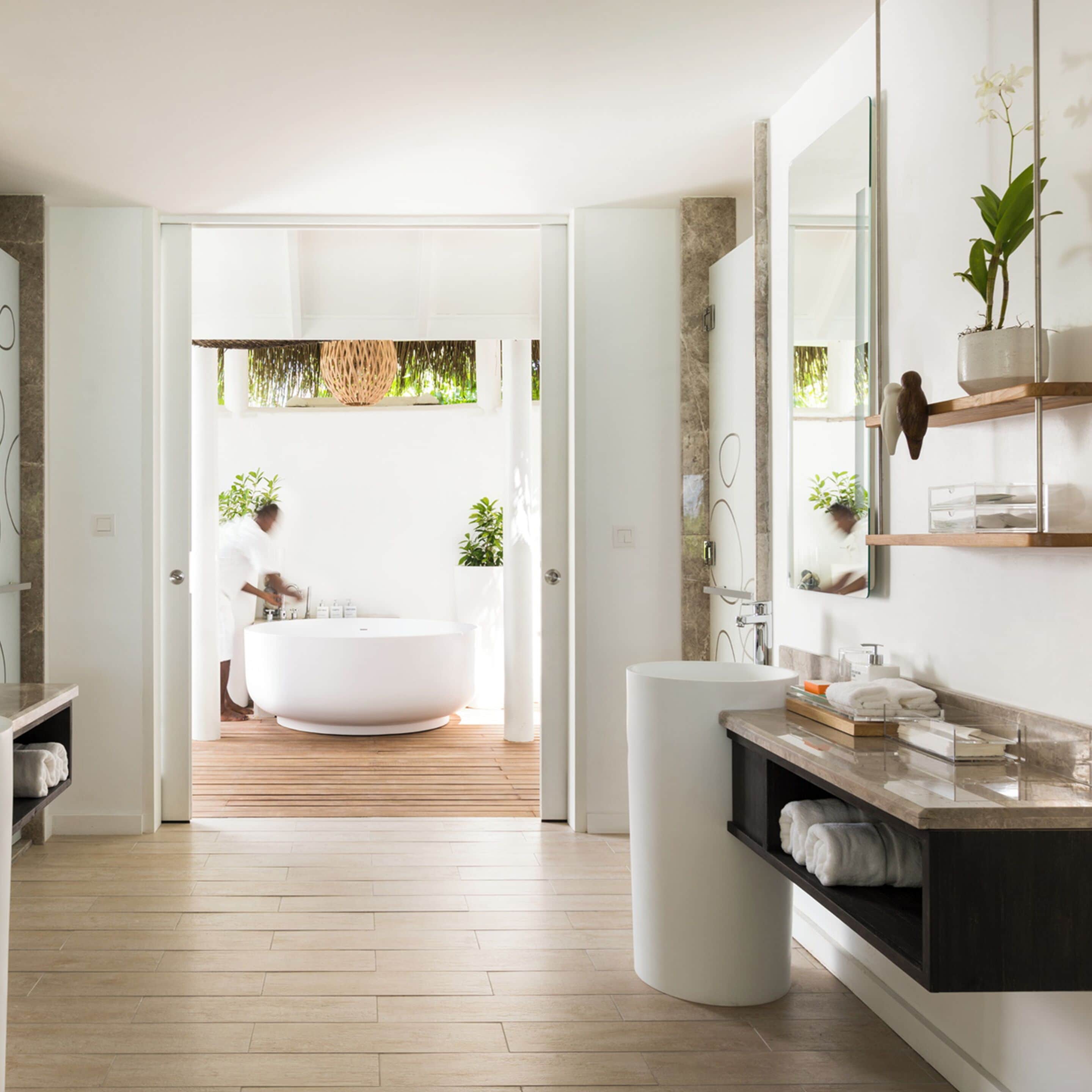 A modern bathroom with a freestanding bathtub, a vanity with a mirror, and a wooden floor.