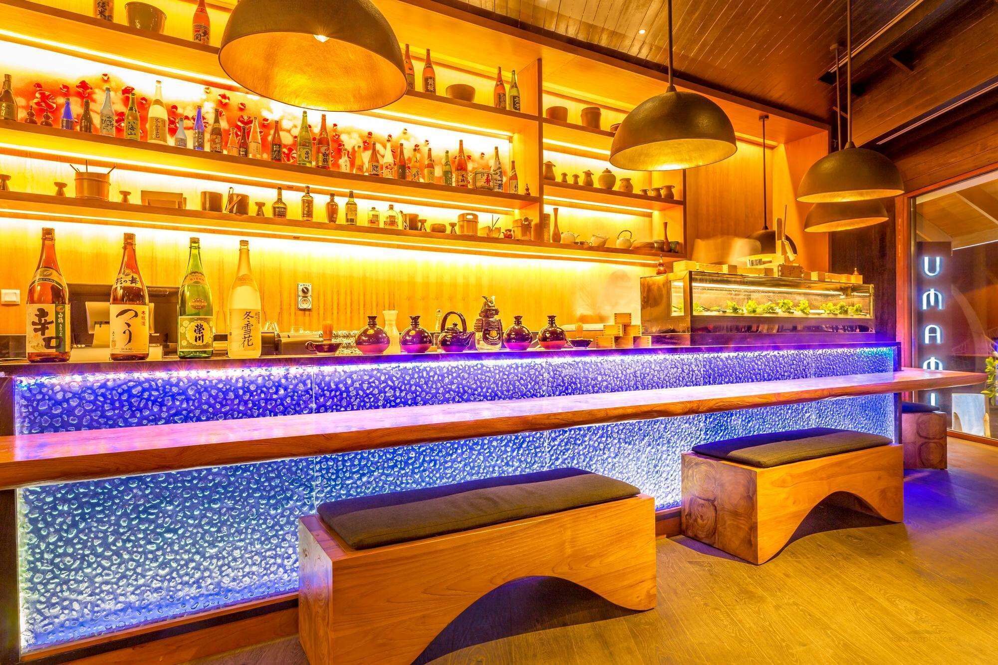 A bar with shelves of bottles and a blue-tiled counter.
