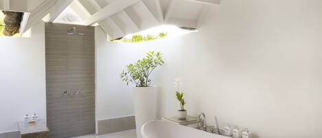 A modern bathroom with a freestanding bathtub, a shower enclosure, and a potted plant.