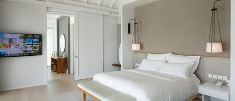 A modern hotel room with a large bed, a TV, and a ceiling fan.