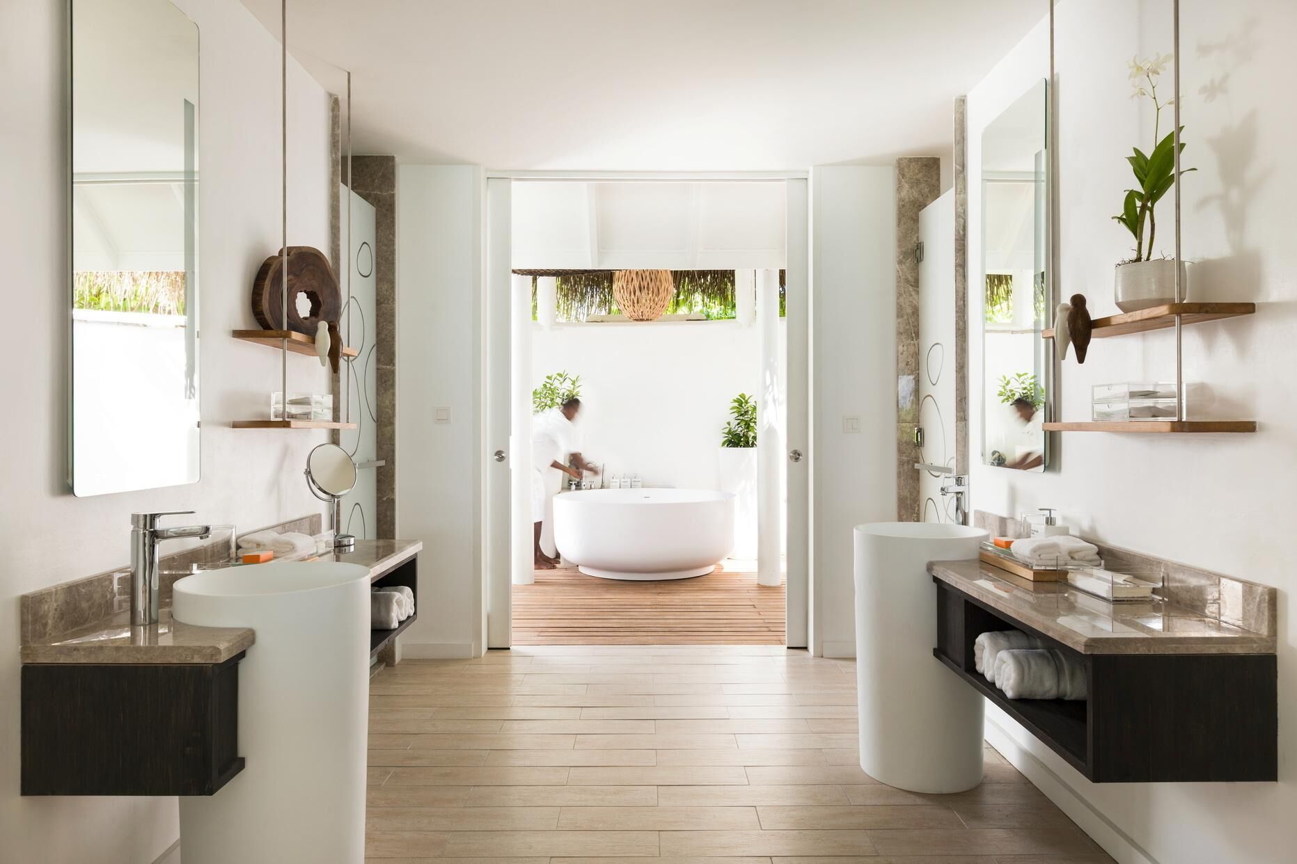 Un baño moderno con una bañera independiente, dos lavamanos y un espejo grande.