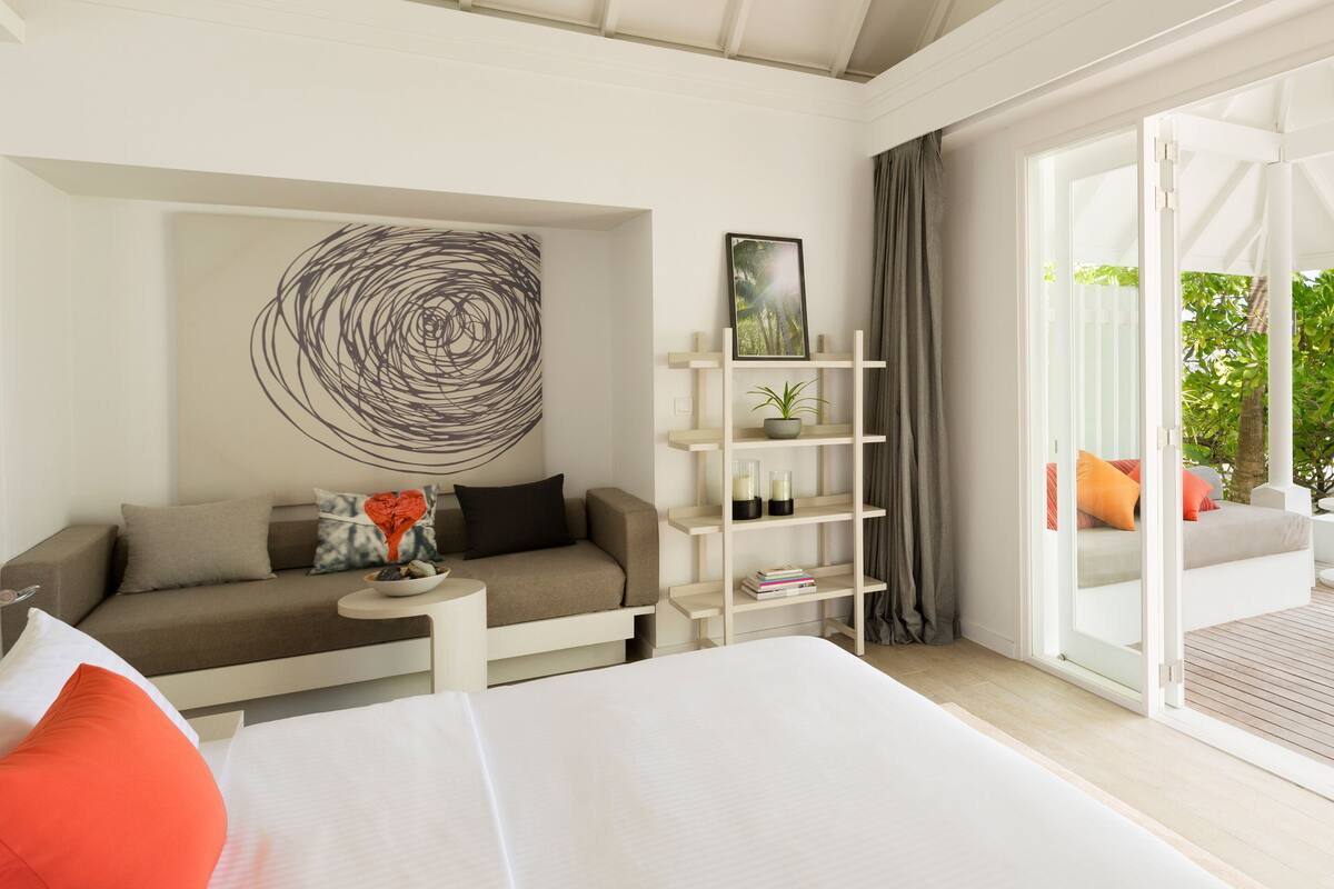 Ein modernes Hotelzimmer mit Bett, einer Couch, einem kleinen Tisch und einem Bücherregal.