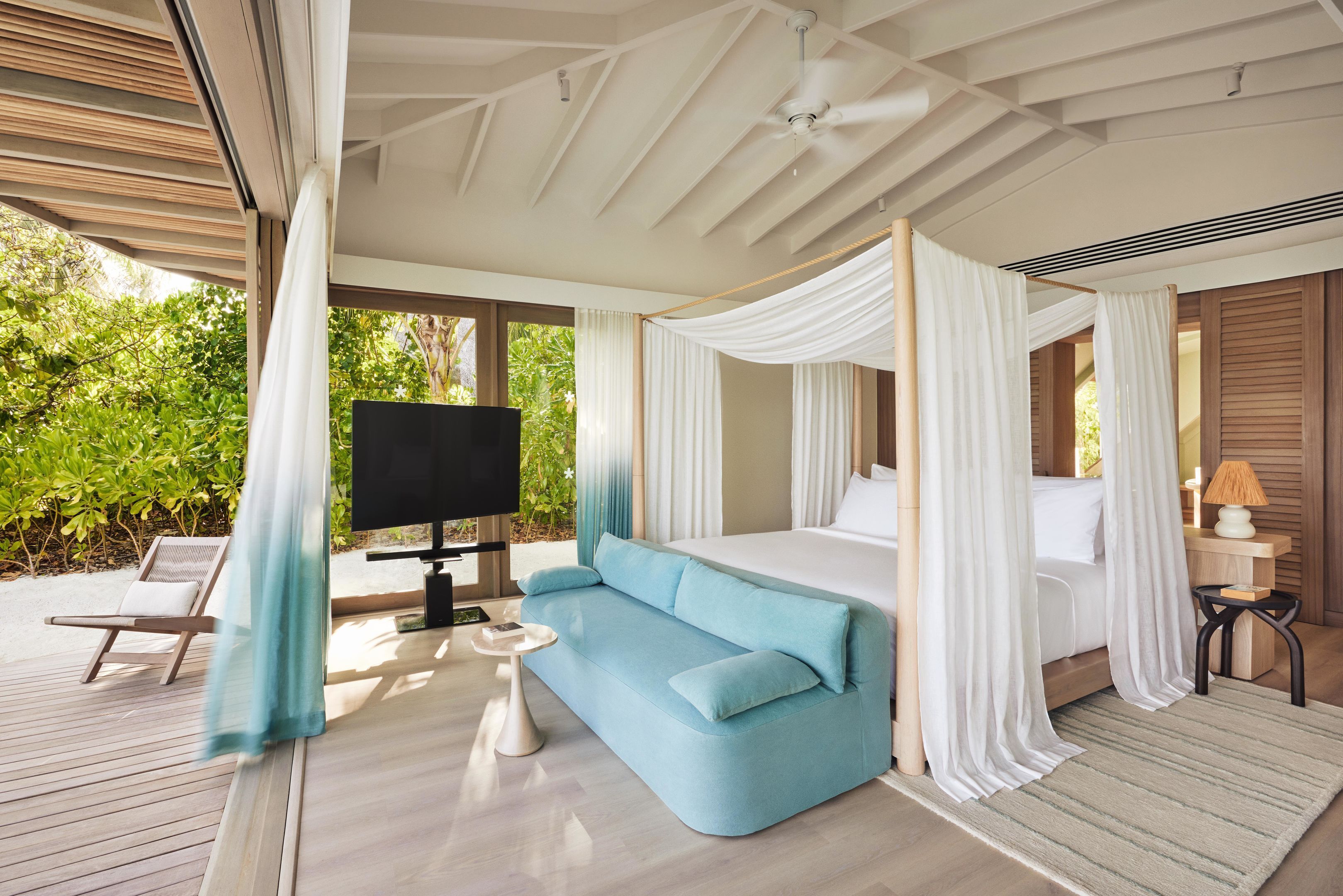 A bedroom with a bed, a TV, a sofa, and a small table.
