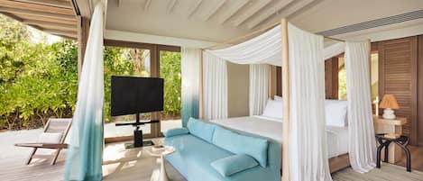 A bedroom with a bed, a TV, a sofa, and a small table.