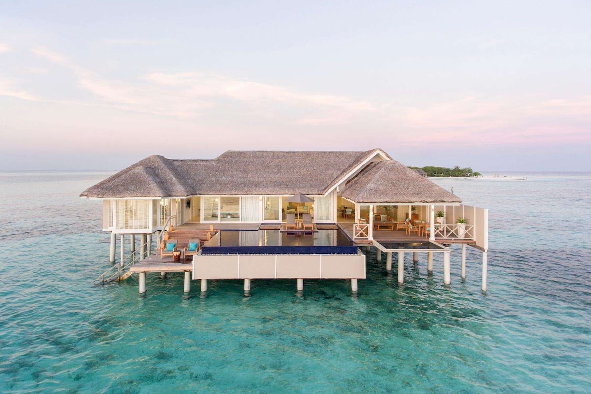 Ein Bungalow über dem Wasser mit Swimmingpool, Deck und Lounge-Bereich.