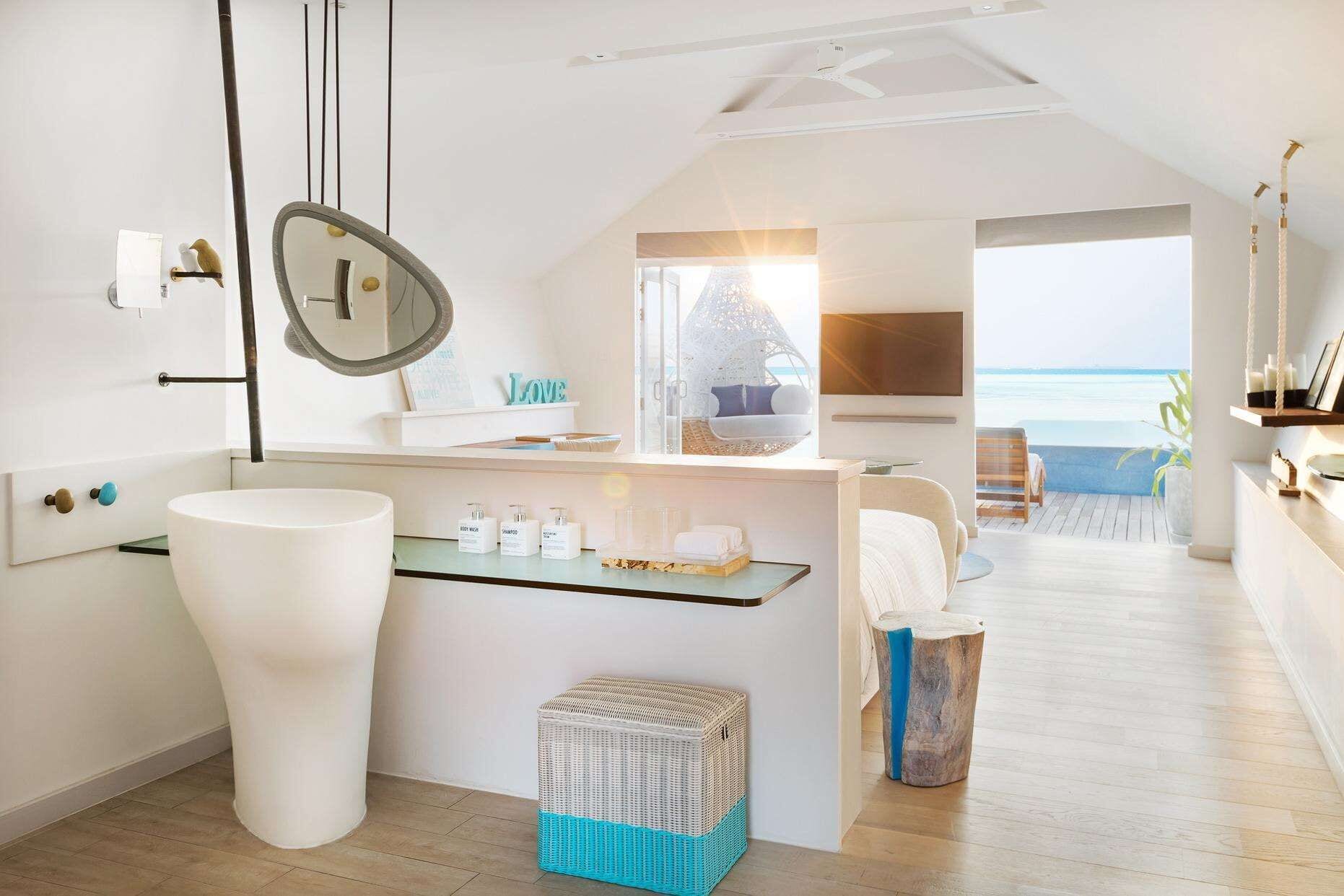 A modern bathroom with a large white sink, a mirror, and toiletries on a glass shelf.