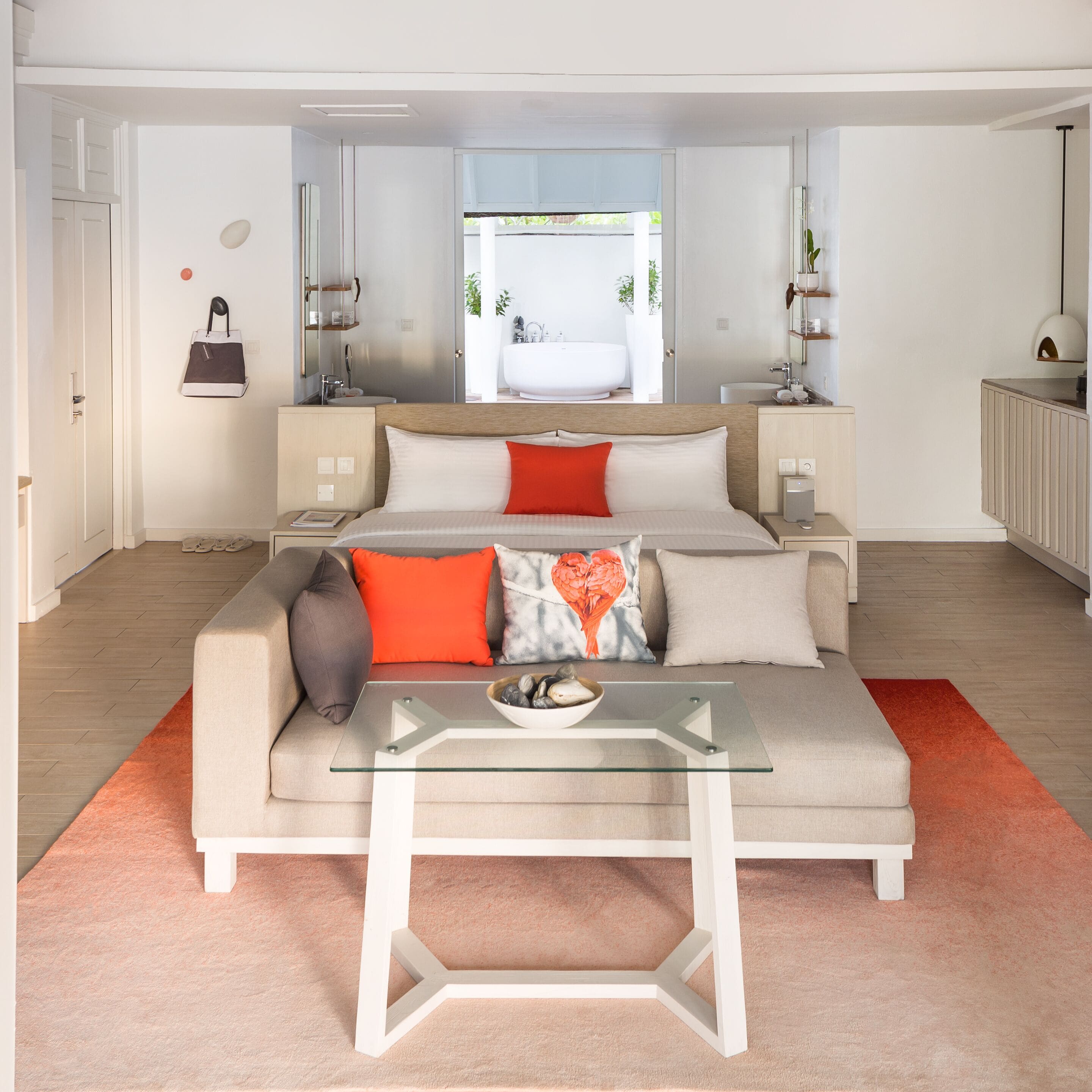 Un dormitorio moderno con una cama grande, una mesa de centro de cristal y vistas a un baño y zona exterior.