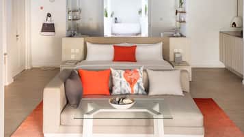 Un dormitorio moderno con una cama grande, una mesa de centro de cristal y vistas a un baño y zona exterior.