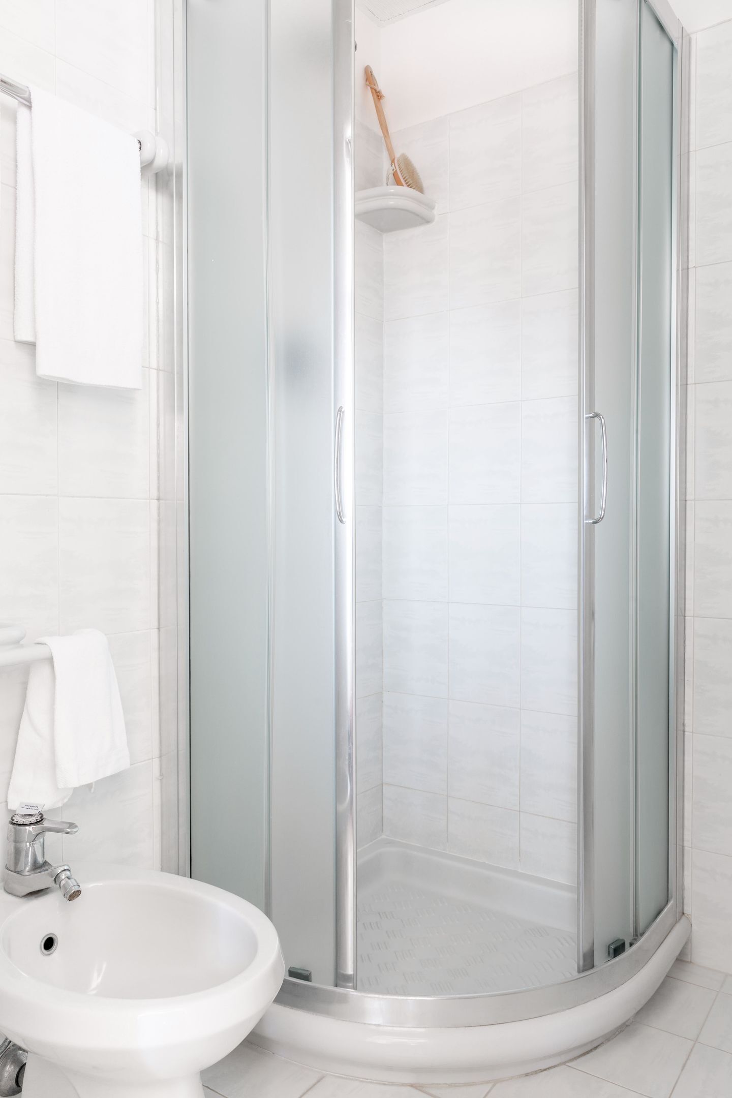 A modern bathroom with a glass-enclosed shower, a white sink, and a towel rack.