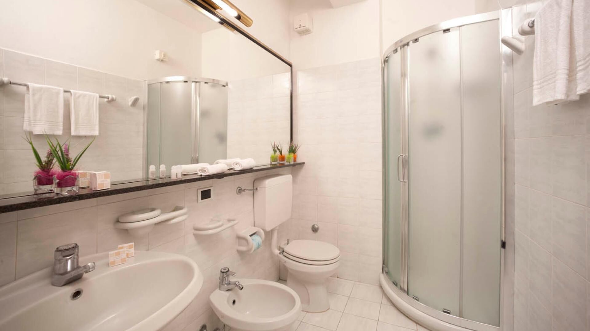 Une salle de bain moderne équipée d’une douche, de deux lavabos, de toilettes et d  ’un miroir.