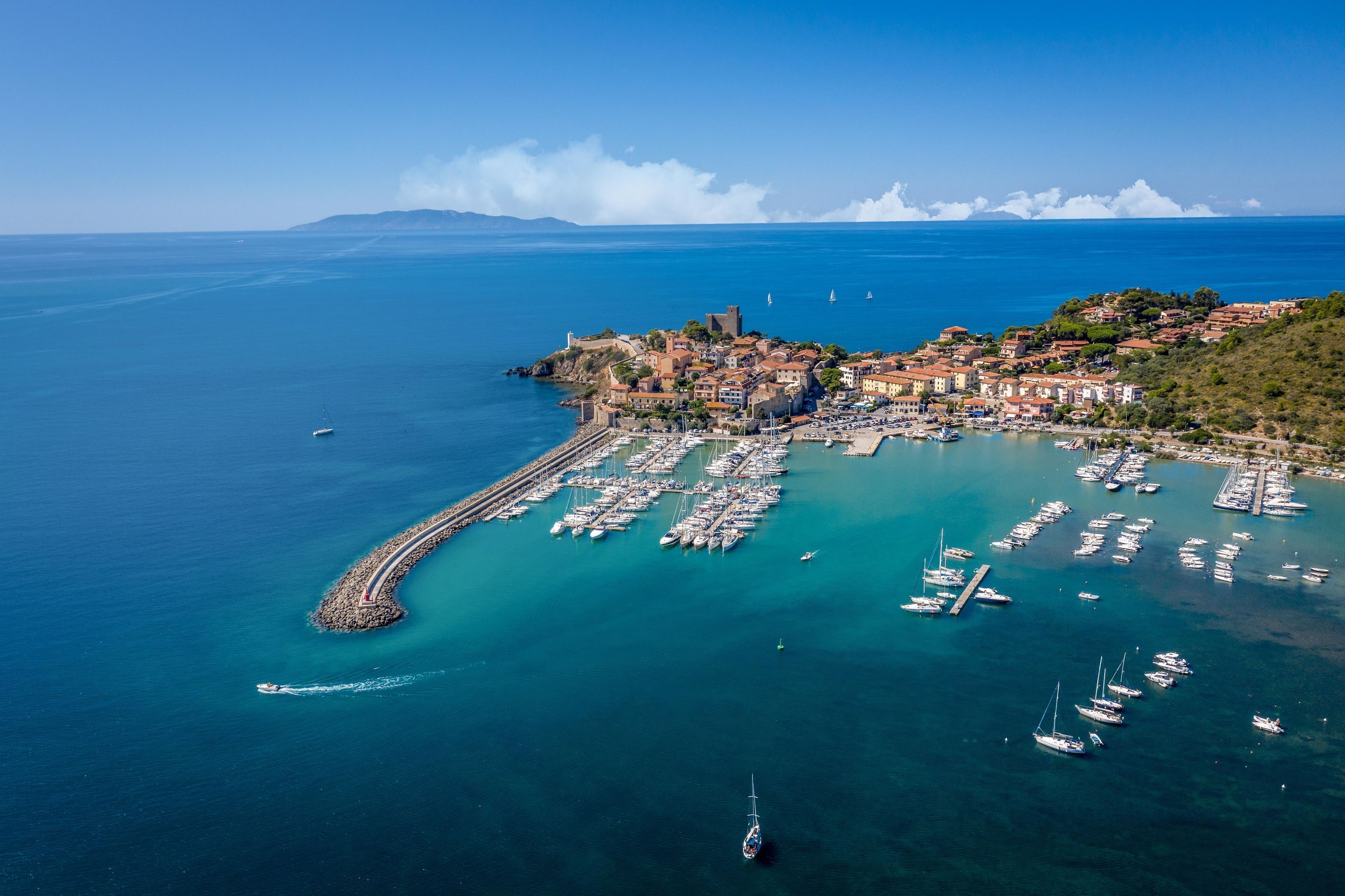 Vue aérienne d’une ville côtière avec un port de plaisance, des bâtiments et un phare.