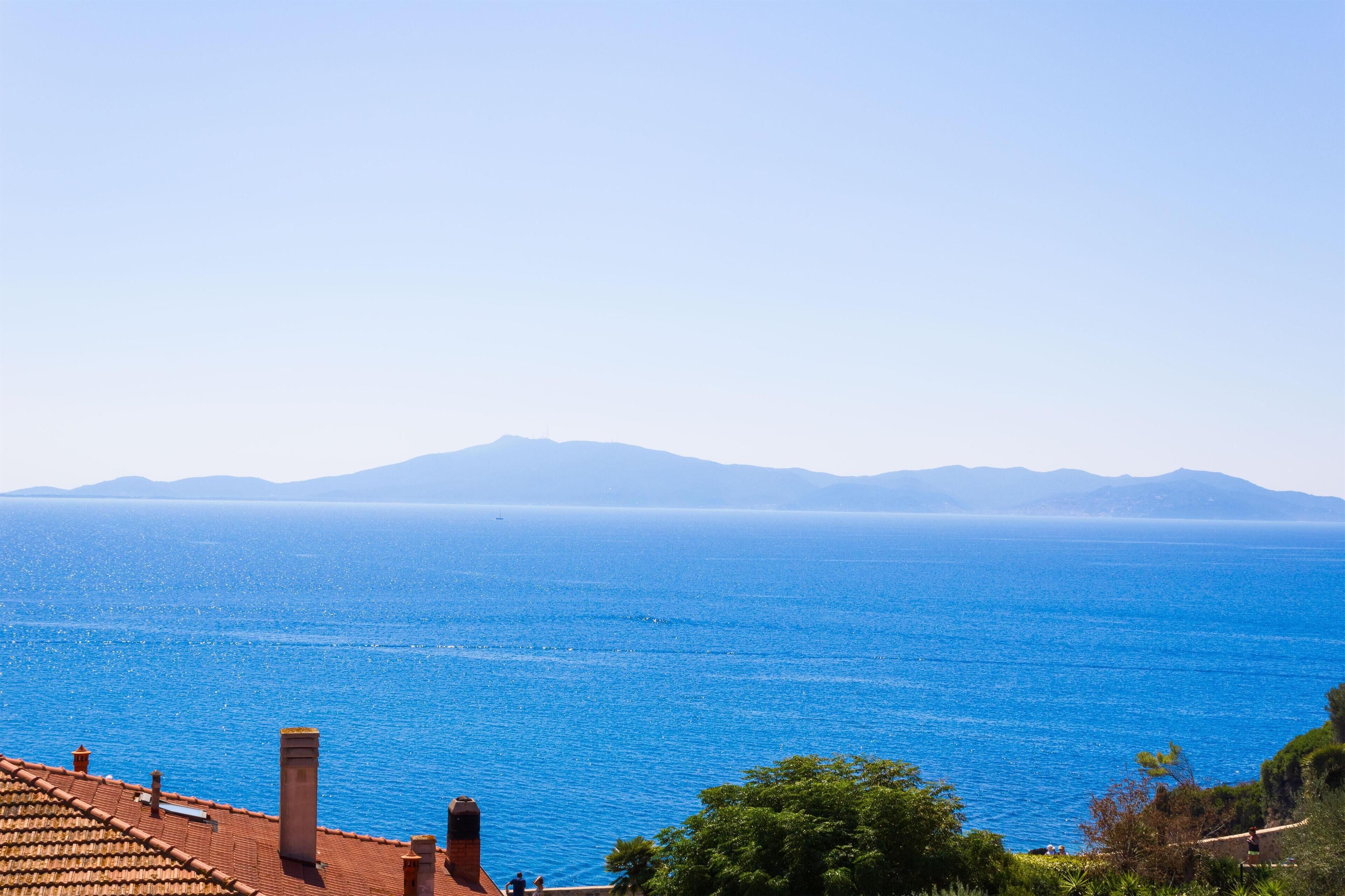 Vista costera con un mar azul cristalino y montañas al fondo.