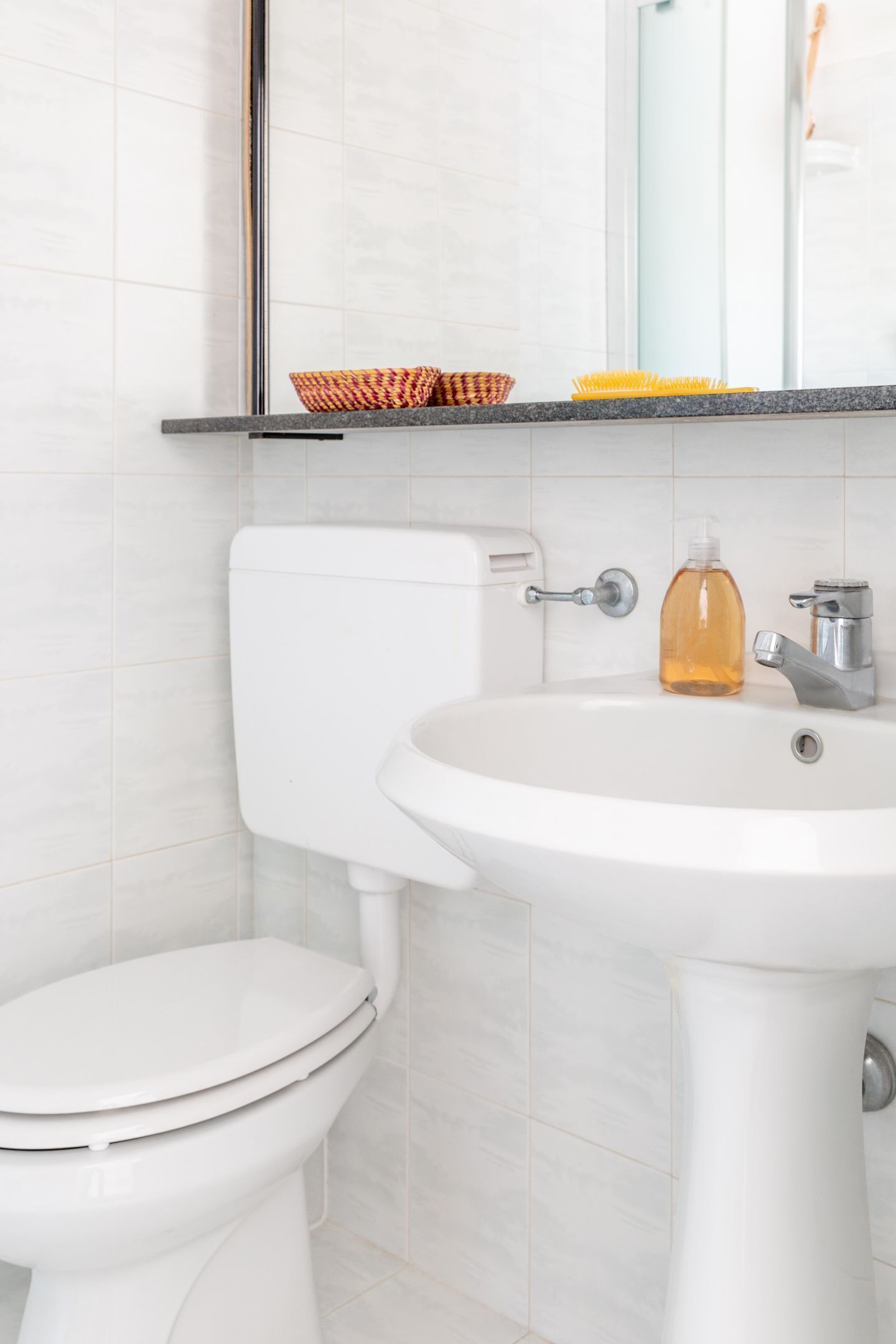 Une salle de bain avec des toilettes, un lavabo et un miroir.
