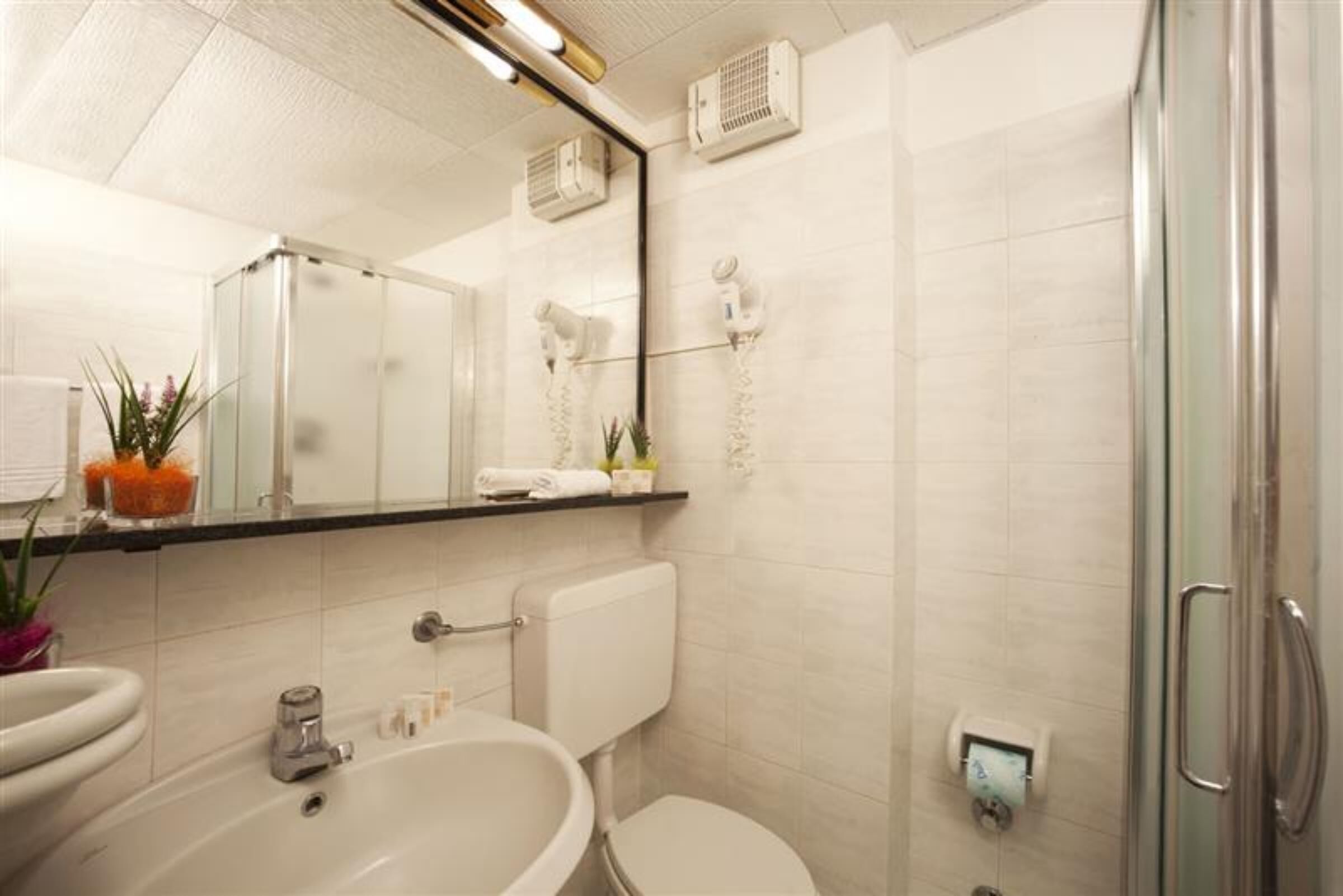 A modern bathroom with a bathtub, toilet, and a glass-enclosed shower area.