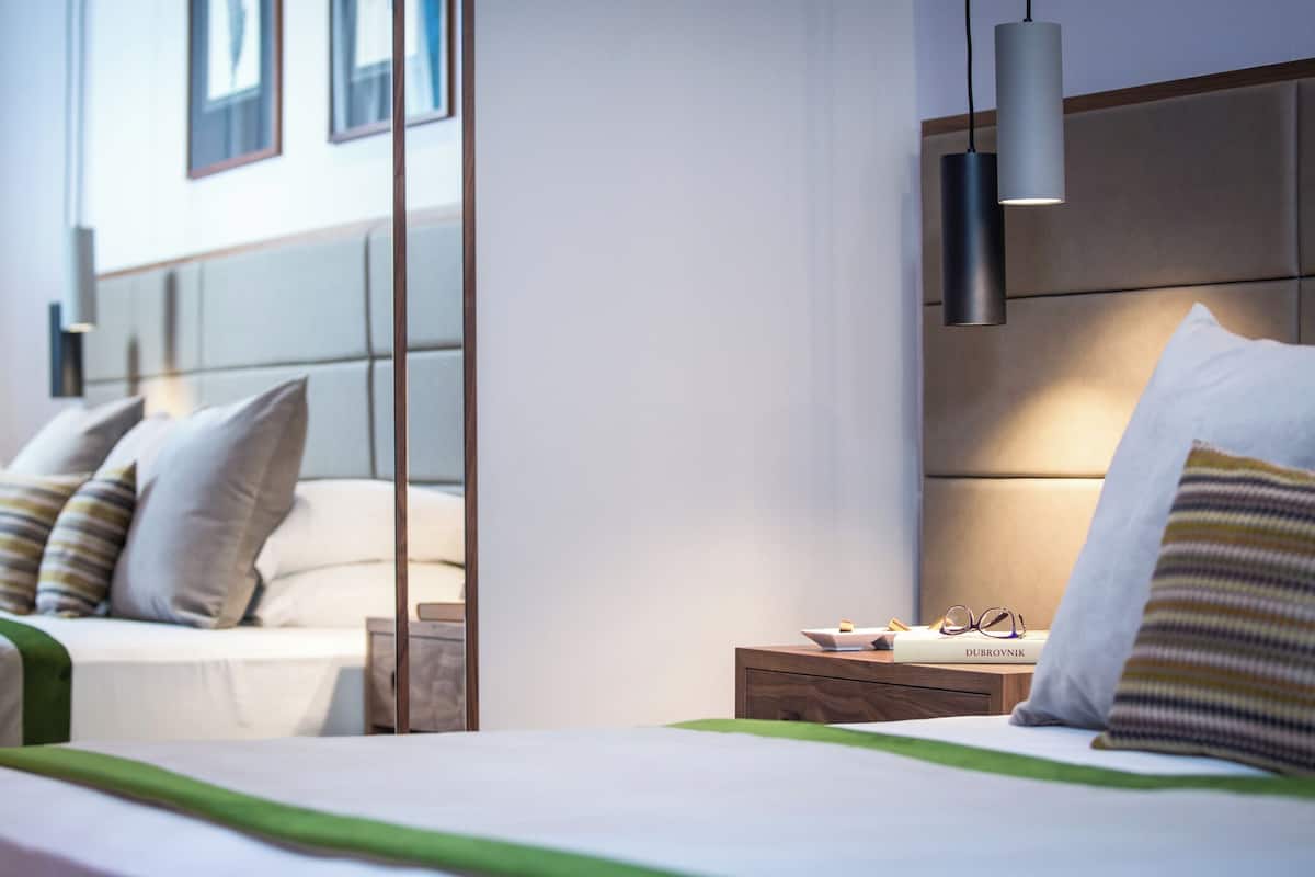 Une chambre d’hôtel avec un lit, une table de chevet et un miroir qui reflète la pièce.