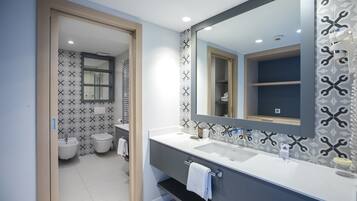 A modern bathroom with a large mirror, a sink, and a toilet.