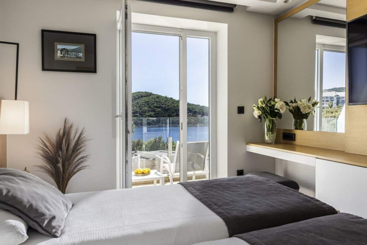 Une chambre à coucher avec un lit, une fenêtre, un balcon et une vue sur une étendue d’eau.