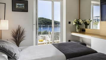 Un dormitorio con cama, ventana, balcón y vista a un cuerpo de agua.