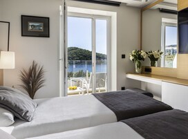 Quarto com cama, janela, varanda e vista para um corpo de água.
