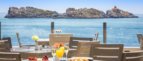 A table set for breakfast with a view of the sea and rocky islands.