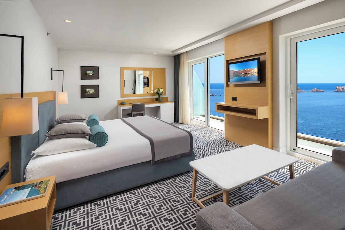 Une chambre d’hôtel moderne dotée d’un grand lit, d’un bureau, d’une télévision et offrant une vue sur la mer.