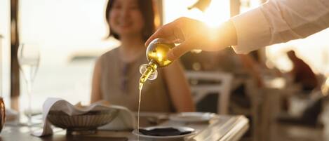 A hand pouring oil into a bowl on a table.