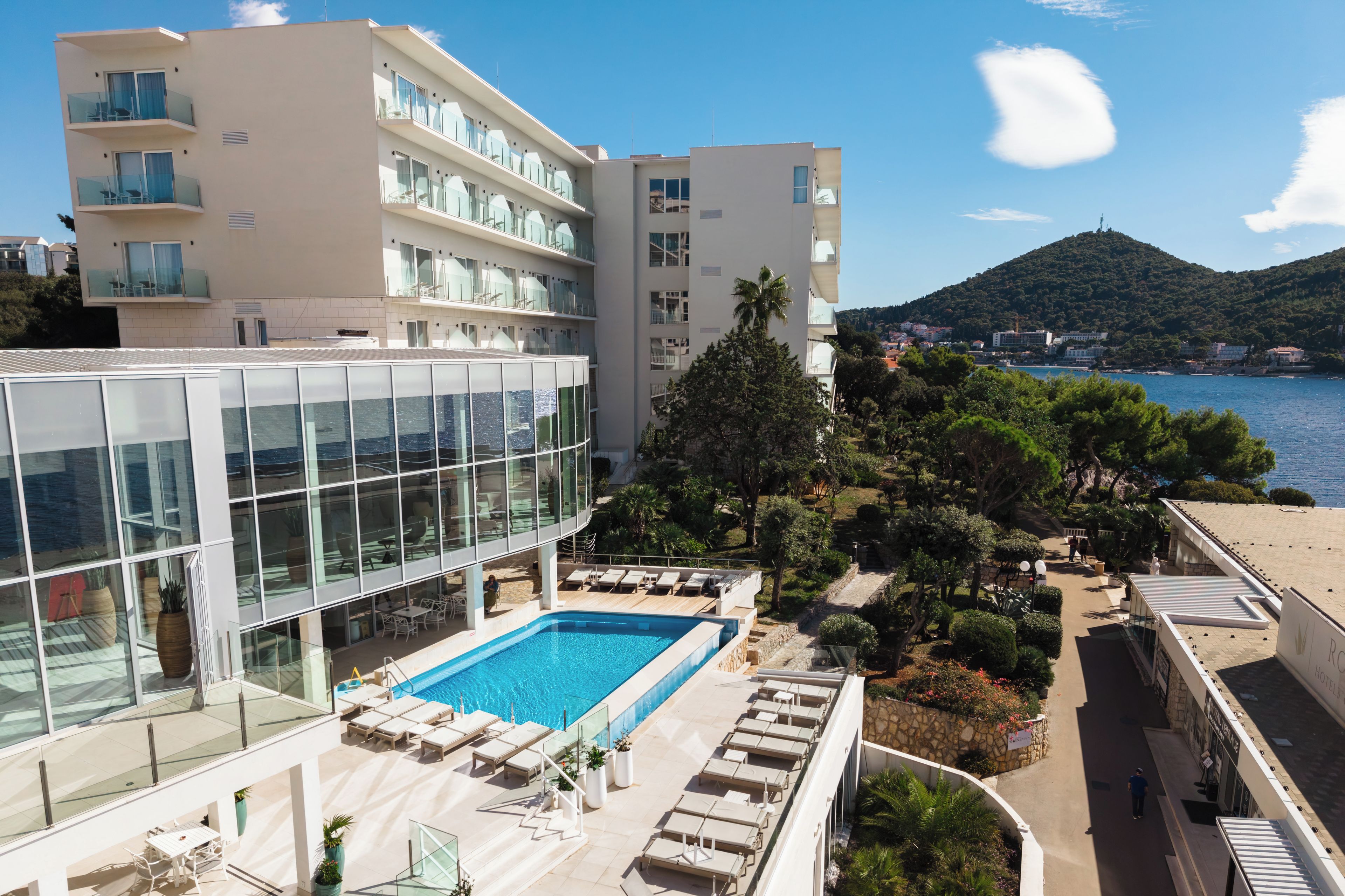 Un hôtel doté d’une piscine, de plusieurs balcons et offrant une vue sur la mer et les collines.