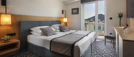 Una habitación de hotel con una cama, lámparas de noche, un escritorio y vistas a la ciudad.