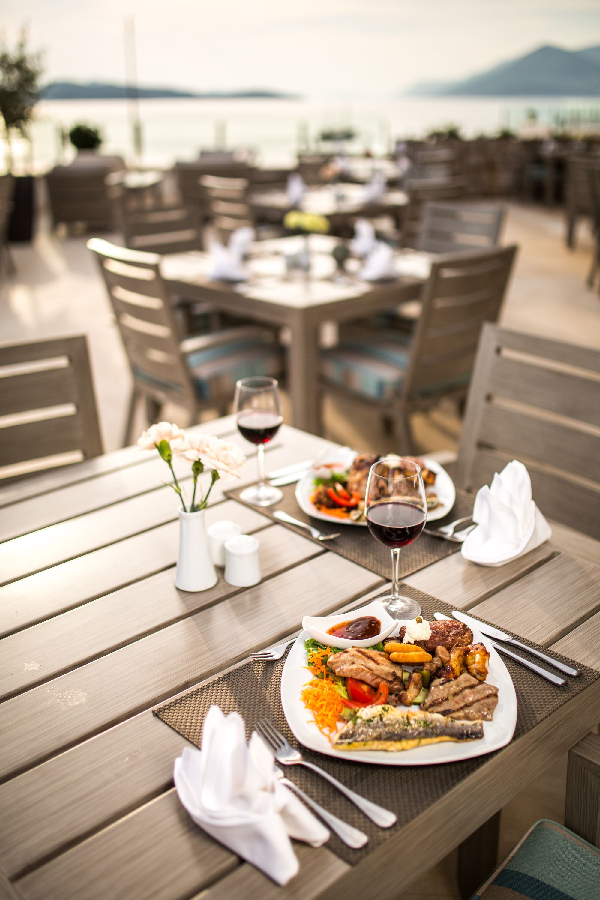 A dining table set with plates of food, wine glasses, and cutlery.