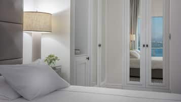 A bedroom with a bed, a nightstand, a lamp, and a view of a balcony with a pool.