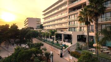 Um hotel com vários andares, com área de estar ao ar livre e palmeiras.