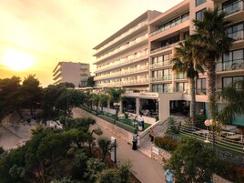 Um hotel com vários andares, com área de estar ao ar livre e palmeiras.
