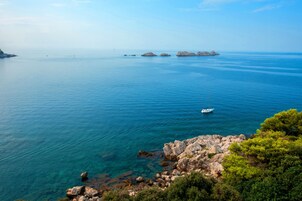 Vista costeira com águas azul-claras, margem rochosa e um barco.