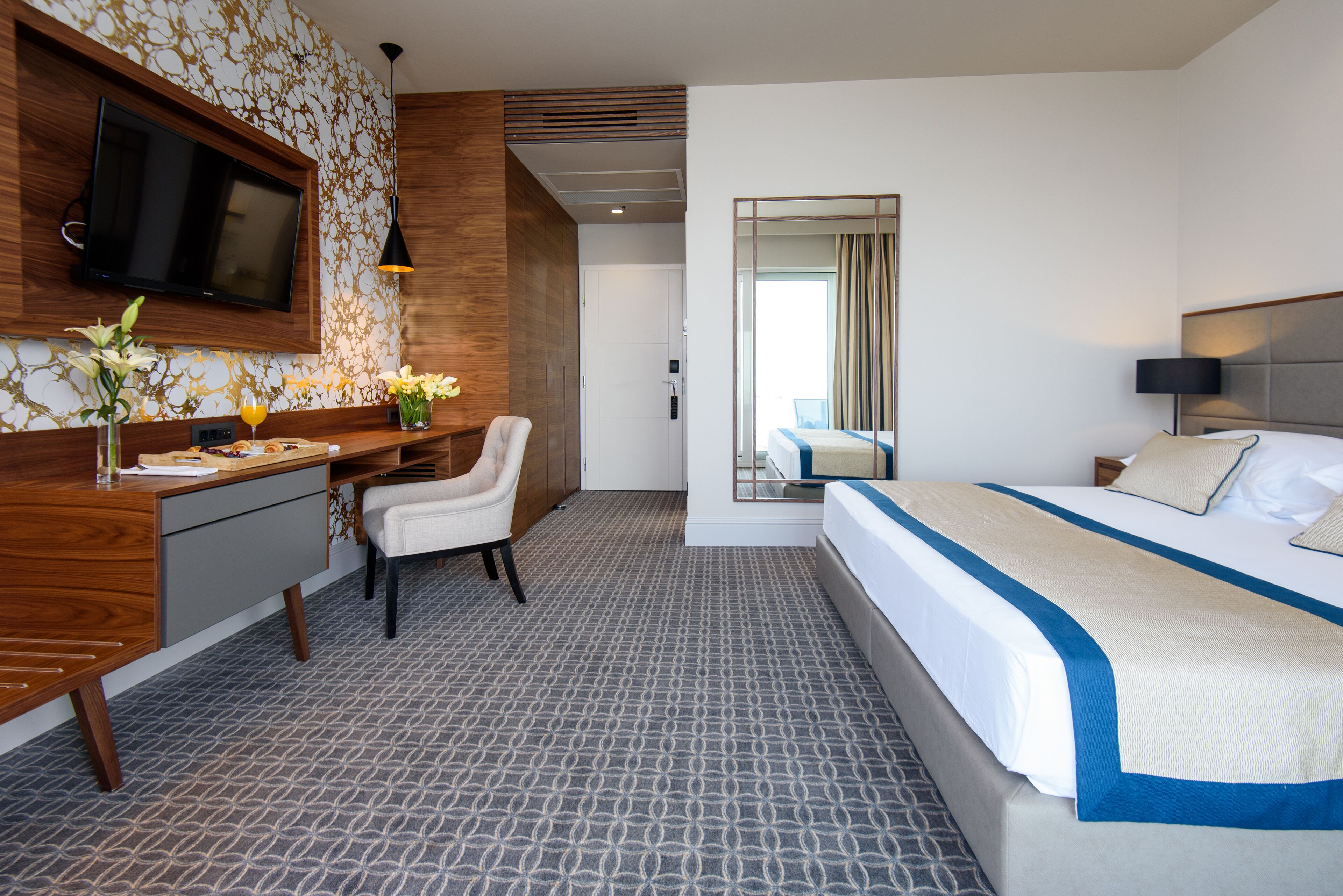 Une chambre d’hôtel équipée d’un lit, d’un bureau, d’une chaise, d’une télévision et offrant une vue sur l’extérieur.