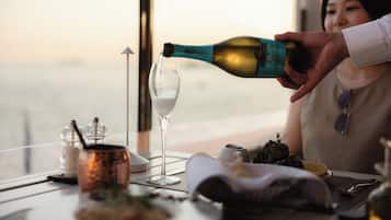 Eine Person gießt ein Getränk in ein Glas an einem Tisch mit Blick auf eine Aussicht.
