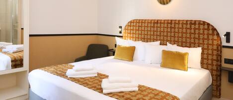 A hotel room with a large bed, a desk, and a chair.