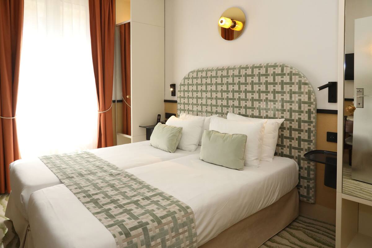 A double bed with a patterned headboard, two bedside tables, and a wall-mounted light fixture.