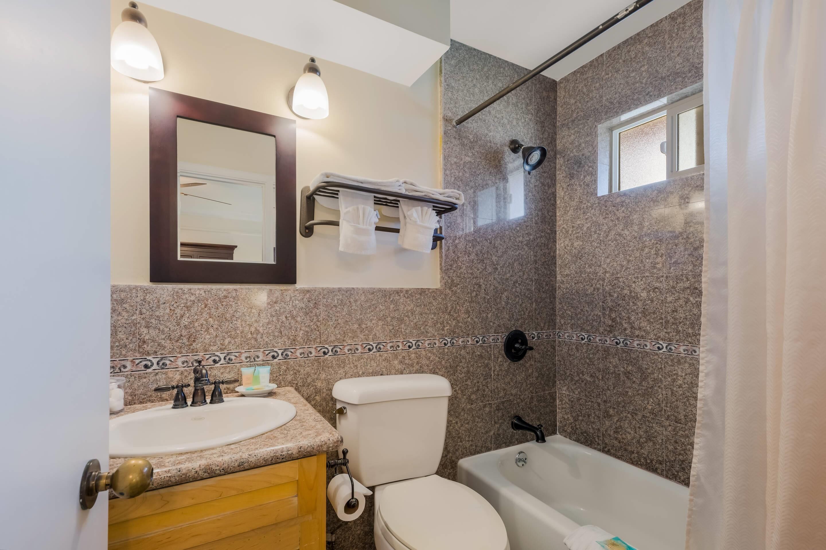 A bathroom with a sink, toilet, and bathtub, a towel rack, and a shower with a window.