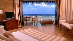 Una habitación con cama, televisión, escritorio, sofá y vista al océano.