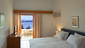 Ein Hotelzimmer mit Bett, Schreibtisch, Computer, Stuhl und Meerblick.