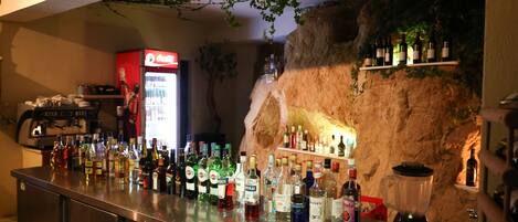 A bar area with a variety of liquor bottles, a blender, and shelves with bottles.