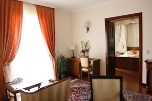 Habitación de hotel con escritorio, silla y cama con dosel.